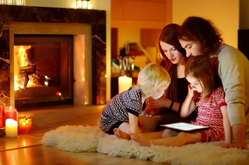 young family look at tablet in front of fireplace at Smoky Mountain cabin