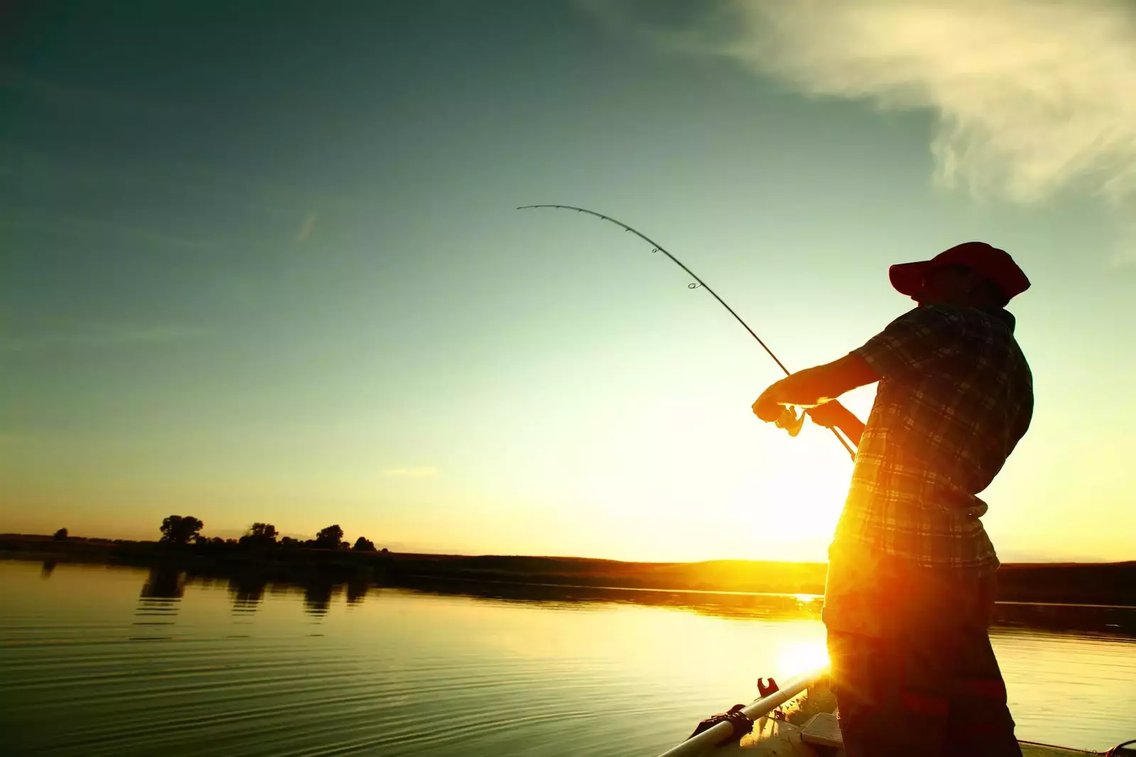 Man fishing on a lake at sunset